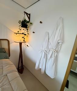 - un peignoir blanc suspendu sur un mur à côté d'un lit dans l'établissement Luxo Boho: Hidro, Alexa Top de linha & +, à Récife