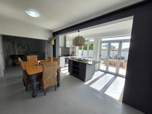 a dining room with a table and chairs and a kitchen at Stoepstories in Yzerfontein