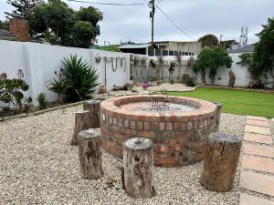 a brick fire pit in a yard with some logs at Stoepstories in Yzerfontein