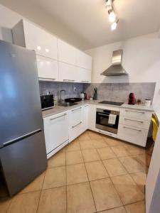 a kitchen with white cabinets and a stainless steel refrigerator at Apartment Banska - City Centre & Private Parking in Banská Bystrica