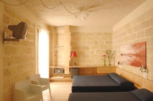 a living room with a bed and a couch and a tv at Cave Bianche Hotel in Favignana