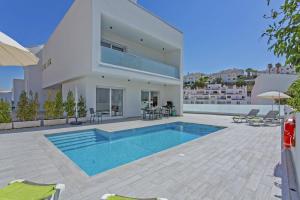 une grande maison blanche avec une piscine dans une cour dans l'établissement Villa Dona Julia by Villa Plus, à Carvoeiro
