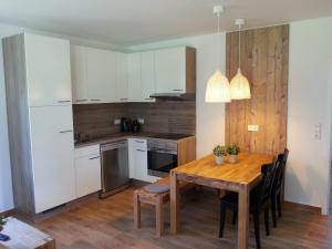OberlangenにあるFerienhaus Biberの木製テーブル付きのキッチン、白いキャビネット付きのキッチン
