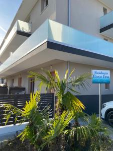 Un cartel delante de un edificio con palmeras. en Casa Eva, en Bibione