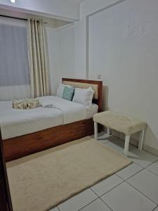 a bedroom with a bed and a bench and a table at Saffron Homes A6 in Eldoret