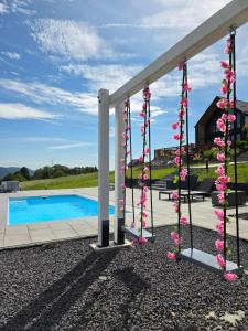 a pergola with pink flowers next to a swimming pool at Lipowe Apartmenty in Limanowa