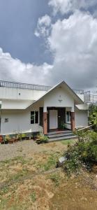 a white house with a yard in front of it at Golden Villa in Vagamon