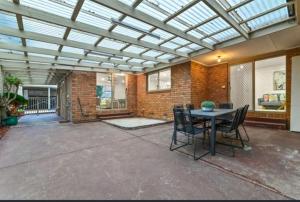 a conservatory with a table and chairs on a patio at Seffa Dom property Melbourne in Springvale South