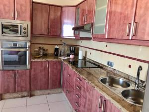 a kitchen with wooden cabinets and a sink at Casa Alejandro II in Tarajalejo