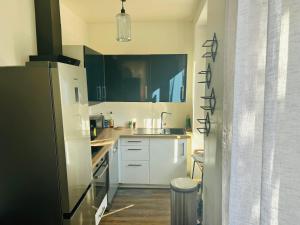 Una cocina con gabinetes blancos y un refrigerador negro. en Chambre d hotes Marseille Prado, en Marsella