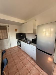 a kitchen with white cabinets and a stainless steel refrigerator at Appartement cosy-parking et jardin privé in Wattignies