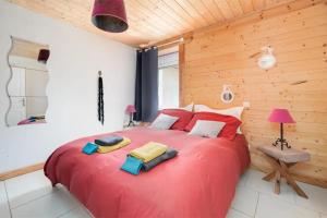 Una gran cama roja en una habitación con una pared de madera. en Piscine Jacuzzi Sauna 4 étoiles, en Uzemain