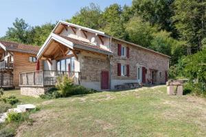 una vieja casa de ladrillo con puertas rojas y un patio en Piscine Jacuzzi Sauna 4 étoiles, en Uzemain