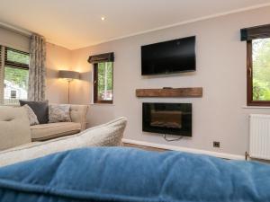 a living room with a fireplace and a flat screen tv at Costapacket in Troutbeck Bridge