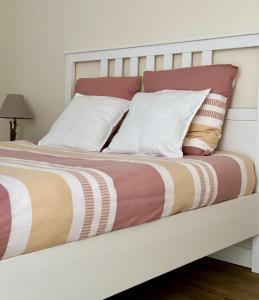 a bed with white and red pillows on it at Bel appartement en rez-de-jardin à 100m des plages in Saint-Nazaire
