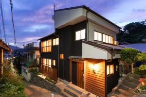 a black house with wooden doors and windows at 一棟貸し 小海の宿 いおり in Numazu