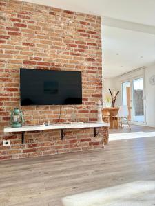 a brick wall with a flat screen tv on it at Bel appartement en rez-de-jardin à 100m des plages in Saint-Nazaire