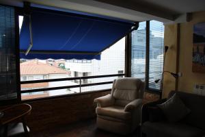 a living room with a chair and a large window at Apartamentos Zarautz Playa4, con piscina y garaje in Zarautz