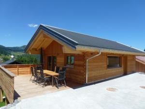 eine Holzhütte mit einem Tisch und Stühlen auf einer Terrasse in der Unterkunft Walser Berg Chalets in Riezlern
