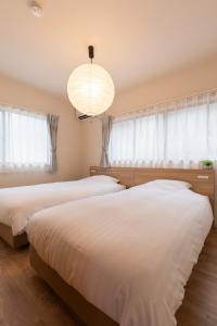 two beds in a bedroom with a chandelier at 一棟貸し 小海の宿 いおり in Numazu