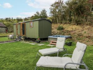 a couple of chairs and a tiny house at Brondel Luxury Shepherd's Hut in Aberystwyth