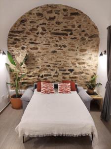 a bedroom with a large bed with a stone wall at La bóveda in Zafra