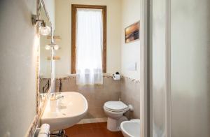 a bathroom with a white toilet and a sink at Bio Agriturismo I Lapi in Catabbio