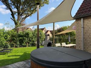 a table with a white canopy in a yard at Pure Wellness Bungalows 52 Sauna&Hottub in Ewijk