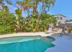 una piscina con sedie, tavolo e palme di Holiday House 3 a Point O'Rocks