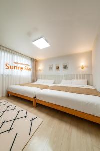 two beds in a bedroom with a sign on the wall at Sunny Stay Inn in Seoul
