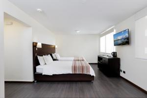 Un dormitorio blanco con una cama y un televisor. en MR Express (ex Hotel Neruda Express), en Santiago