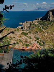 a woman laying in a swimming pool near the ocean at QUIETE e MARE in San Vito lo Capo
