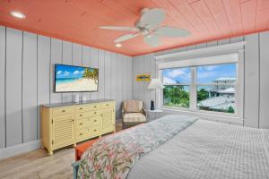 a bedroom with a bed with a ceiling fan and a television at Salty Margarita in Anna Maria Island