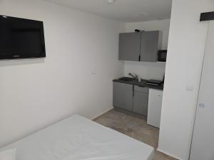 a white kitchen with a tv on the wall at Canto Cigalo Rdc 2 in Robion en Luberon