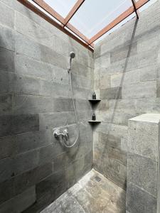 a shower in a bathroom with a stone wall at Langit Wanagiri in Gitgit +25 photos