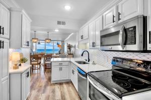 een keuken met witte kasten en een kookplaat oven bij Shimmering Shores in Anna Maria Island
