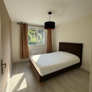 Un dormitorio con una cama en una habitación con ventana. en Grand appartement 2 chambres lumineux et moderne à Honfleur, en Honfleur