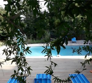 Una piscina con dos sillas azules en primer plano. en Villa Les Escouls, en Ribes