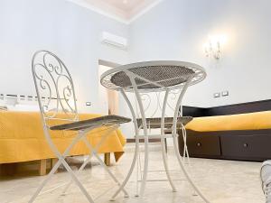 two chairs and a table in a room with a bed at Epoque in Messina