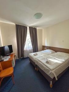 a bedroom with a bed and a desk and a television at Corvin Hotel in Győr