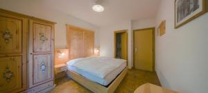 a bedroom with a white bed and a wooden cabinet at Locanda Maria in Vigo di Fassa