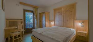 a bedroom with a bed and a desk and a window at Locanda Maria in Vigo di Fassa