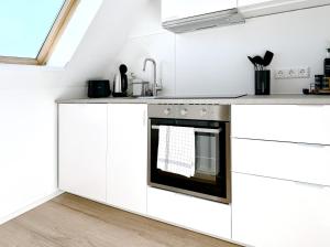 Una cocina con gabinetes blancos y un horno. en Turmblick - Parkplatz - A7 Nähe - Bahnhof Nähe - mit WM, en Illertissen