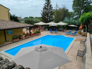 a pool with an umbrella and chairs and umbrellas at Il Giardino Dei Limoni in Montecassiano