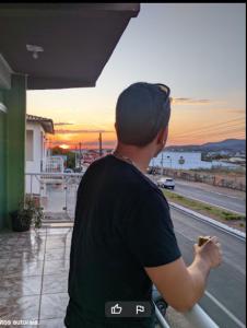a man standing on a balcony eating a sandwich at Kuawit Hotel in Aragarças