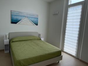 Un dormitorio con una cama verde y una ventana. en Casa al mare di Nonno Robi, en Fano
