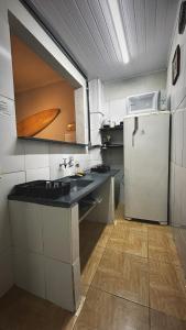 a small kitchen with a refrigerator and a sink at Chalé Privativo Surfers Itaguá in Ubatuba