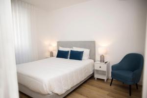 a bedroom with a bed and a blue chair at Casa Dona Isabel - ocean suites in Lagoa +32 photos