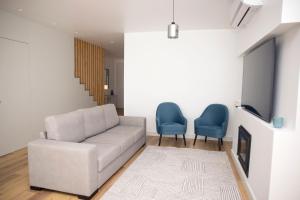 a living room with a couch and two blue chairs at Casa Dona Isabel - ocean suites in Lagoa