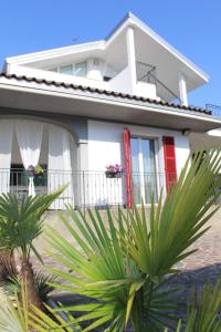 a white house with palm trees in front of it at BF SUITE Foresteria Bellusci in Rho